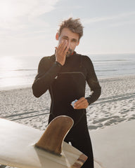 Surfer applying sunscreen from a Cadence Capsule - main-only